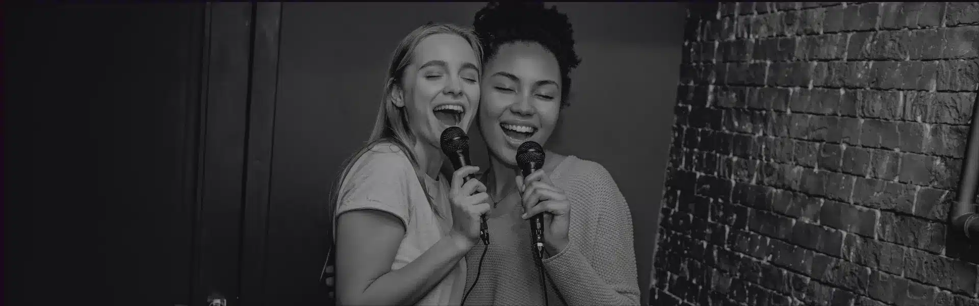 twee vrouwen die karaoke zingen, als blogbanner voor het tweede deel van de zomerserie 'op de camping', erotisch verhaal voor lesbische en biseksuele vrouwen op Queerina.nl